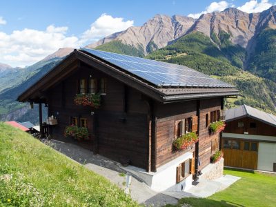 MOREL, SWITZERLAND - SEPT. 24, 2017: Traditional swiss chalet with flowers, in a mountainous landscape with solar energy panels on the roof.