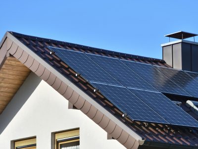 Solar panels installed on the roof of a house with tiles in Europe against the background of a blue sky.